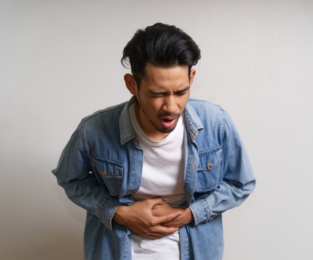 Male Pelvic Floor Physiotherapy Edmonton At Vertex Physiotherapy With Young Asian Man Holding His Lower Abdomen In Discomfort